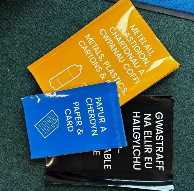 Colour-coded stickers for recycling, labelled in Welsh and English for metals, plastics, paper, and non-recyclables